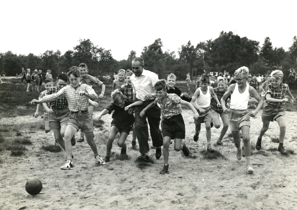 Voetballende jongens van de Prinses Ireneschool 1957. In het midden hoofdmeester Gernaat. Brildragend twee van rechts ren ik mee op kousenvoeten. Deze foto stond in de middageditie van het Nieuwblad van het Noorden. Mijn moeder vroeg na terugkomst waarom ik mijn schoenen niet aanhad! Had ze al gezien op die foto!